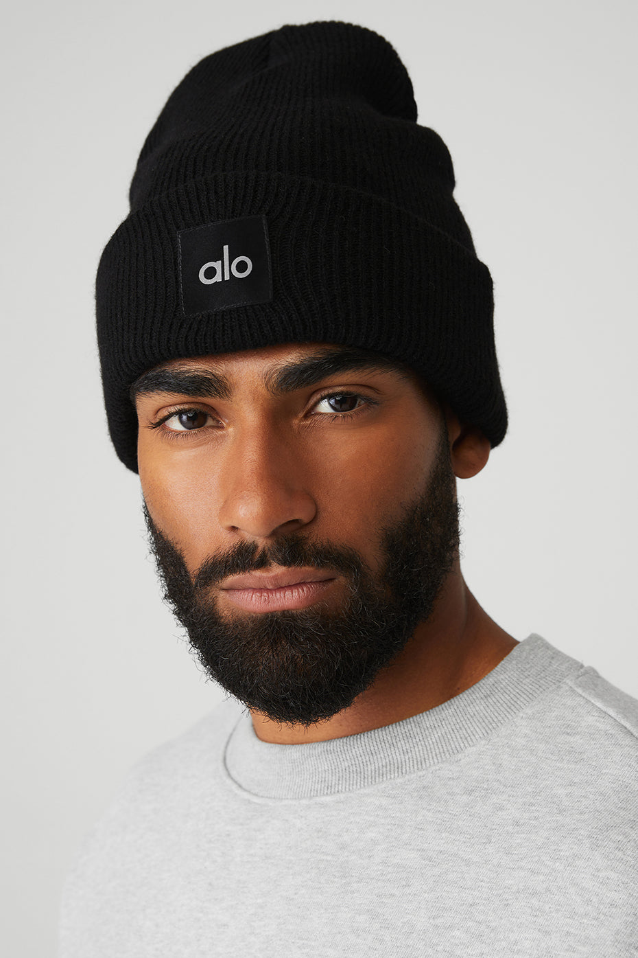 Front view of a black beanie on a model in winter setting