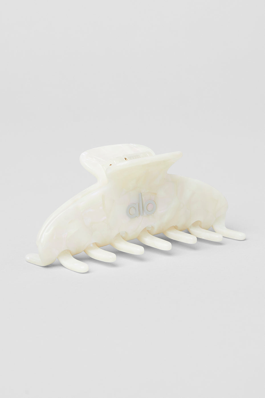 Close-up of a white pearl claw clip with a sleek design on a model's hair