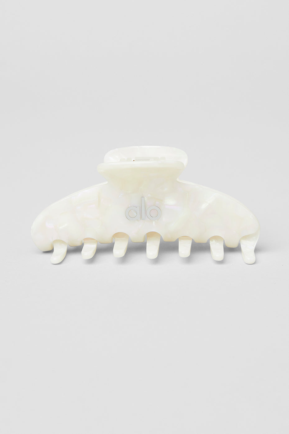 Flat claw clip with pearl detail holding a messy bun in a bright room