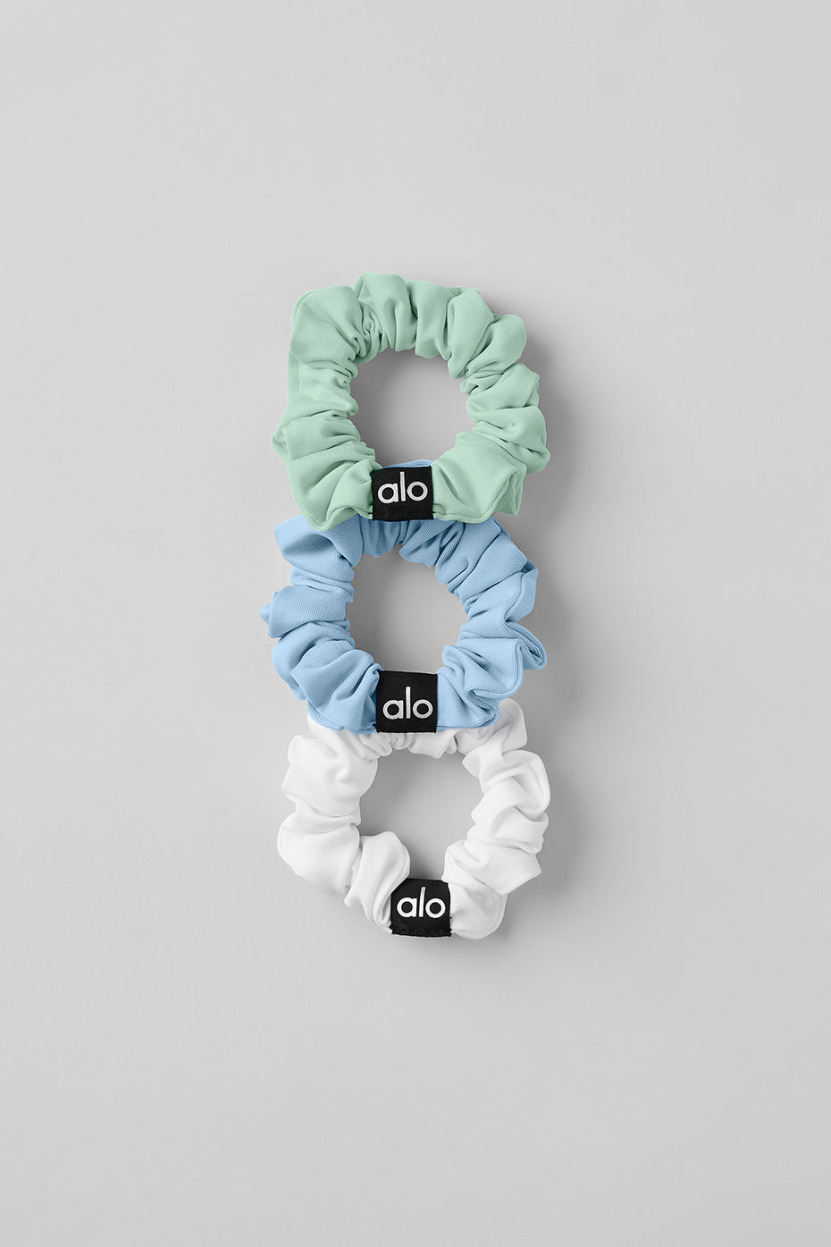 Close-up of mini silk scrunchies in white, seashell blue, and spearmint.