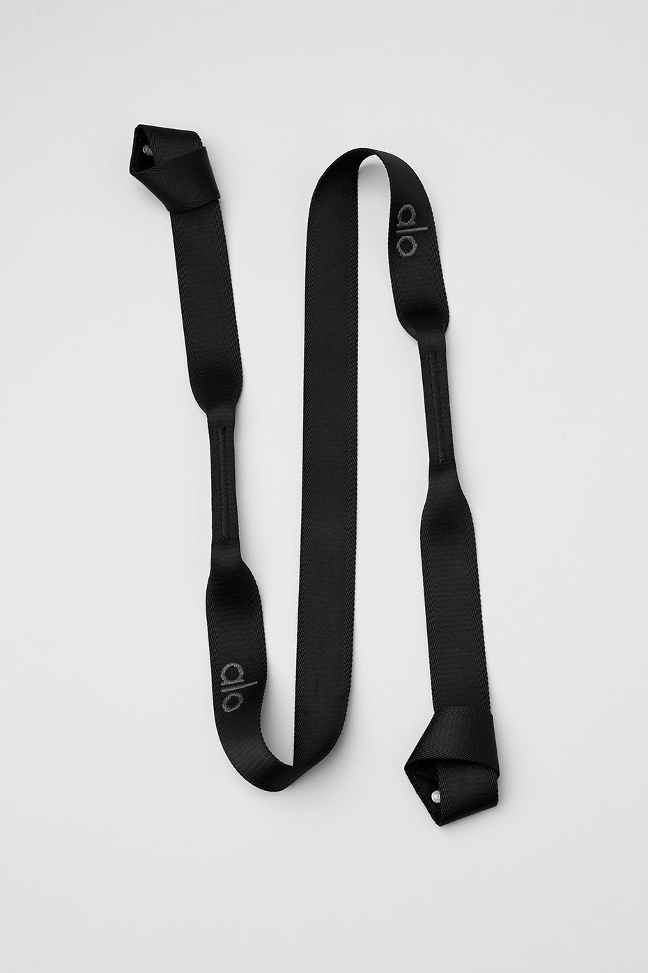 Black yoga mat strap demonstrating support during a stretch.