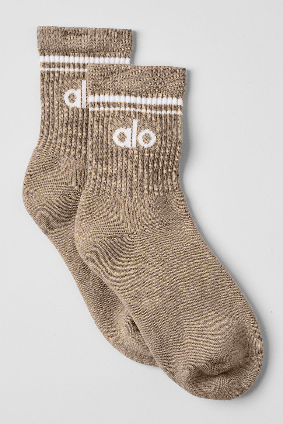 Close-up of gravel and white unisex half crew throwback socks on a wooden floor.