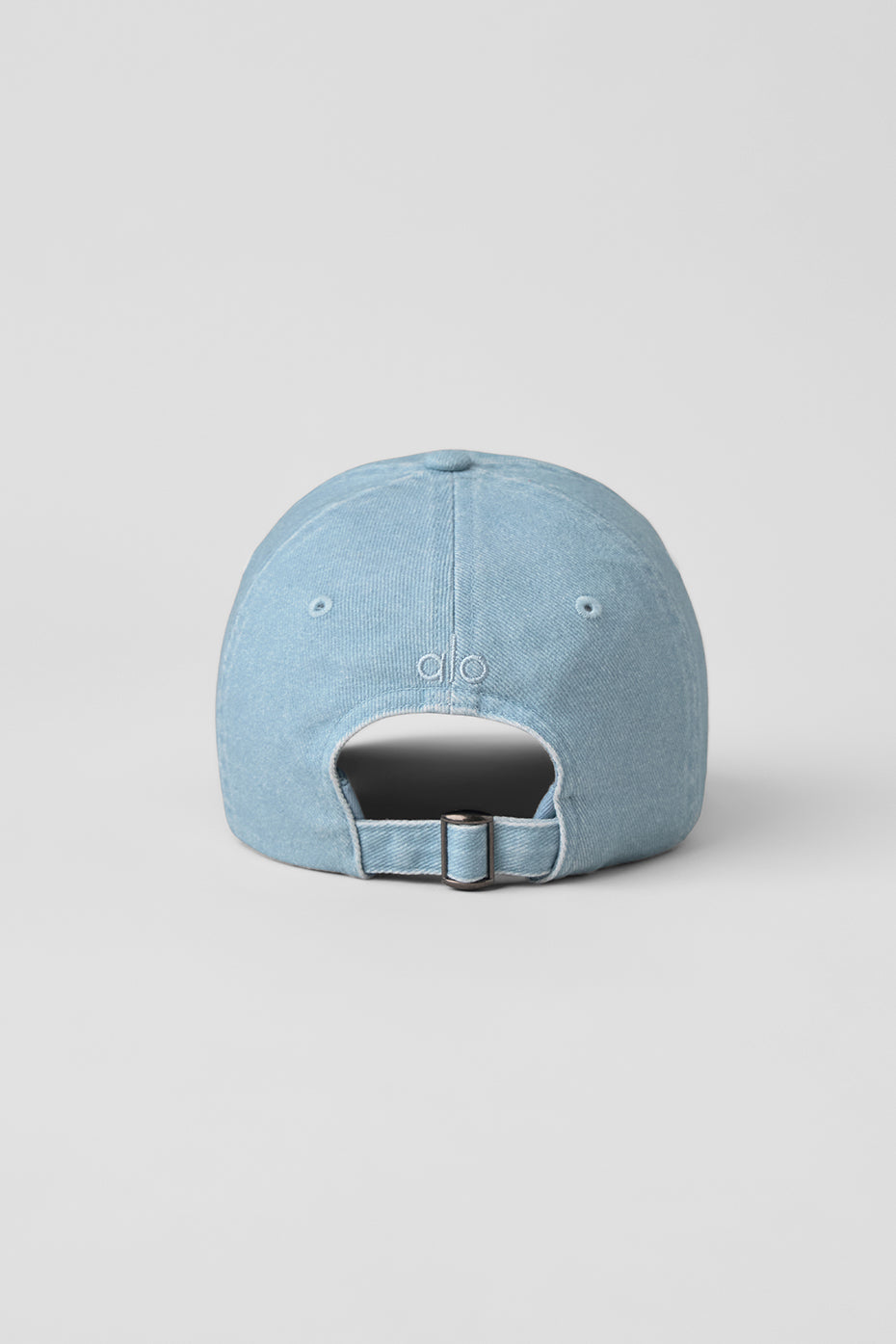 Close-up of adjustable buckle on washed denim cap