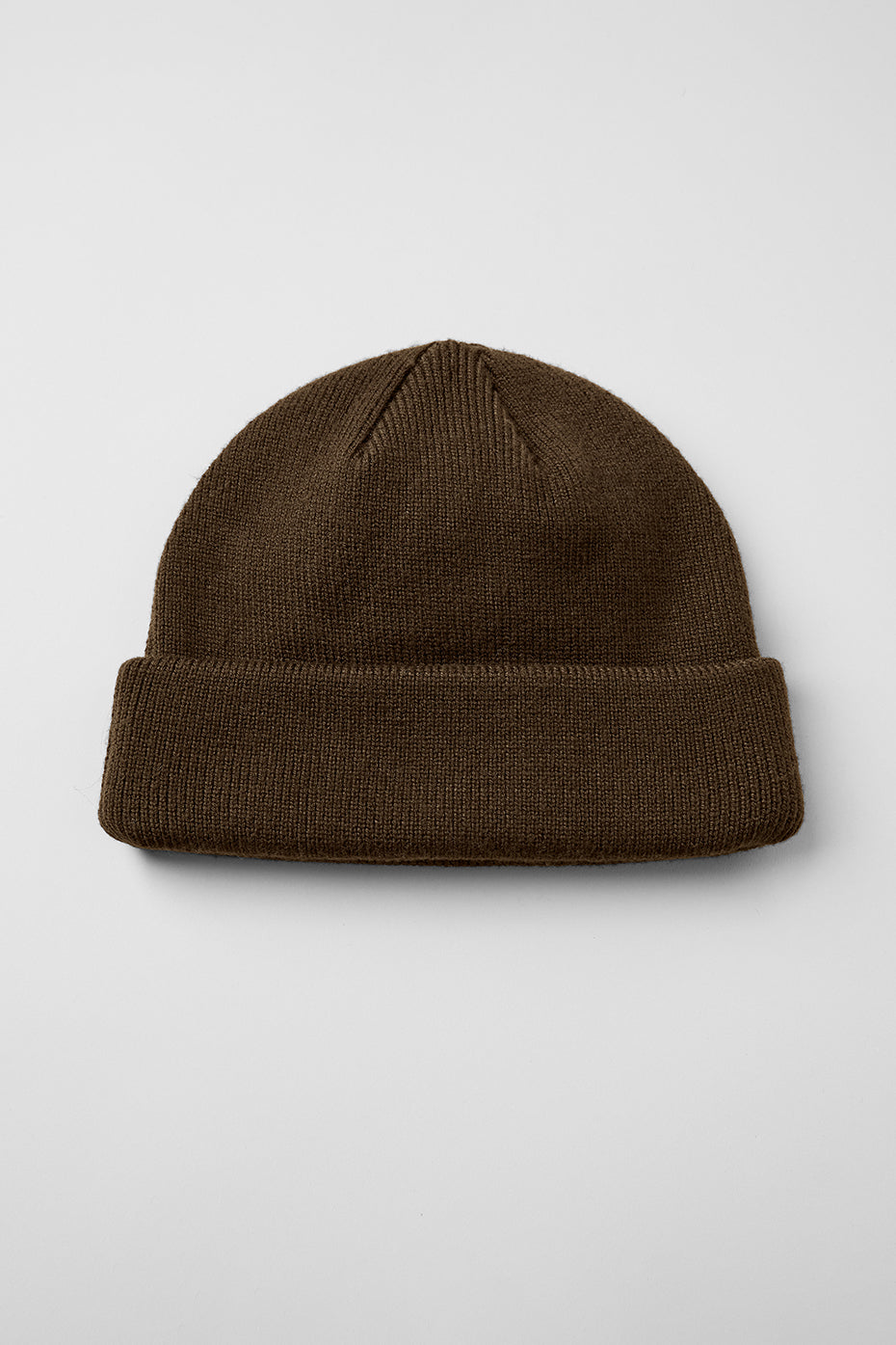 Model wearing stylish beanie with ALO logo in urban setting.
