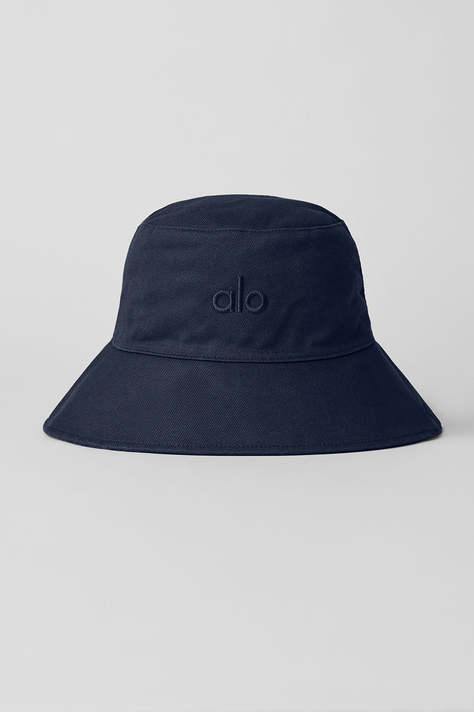 Front angle of navy bucket hat folded on a canvas tote, designed for casual wear.