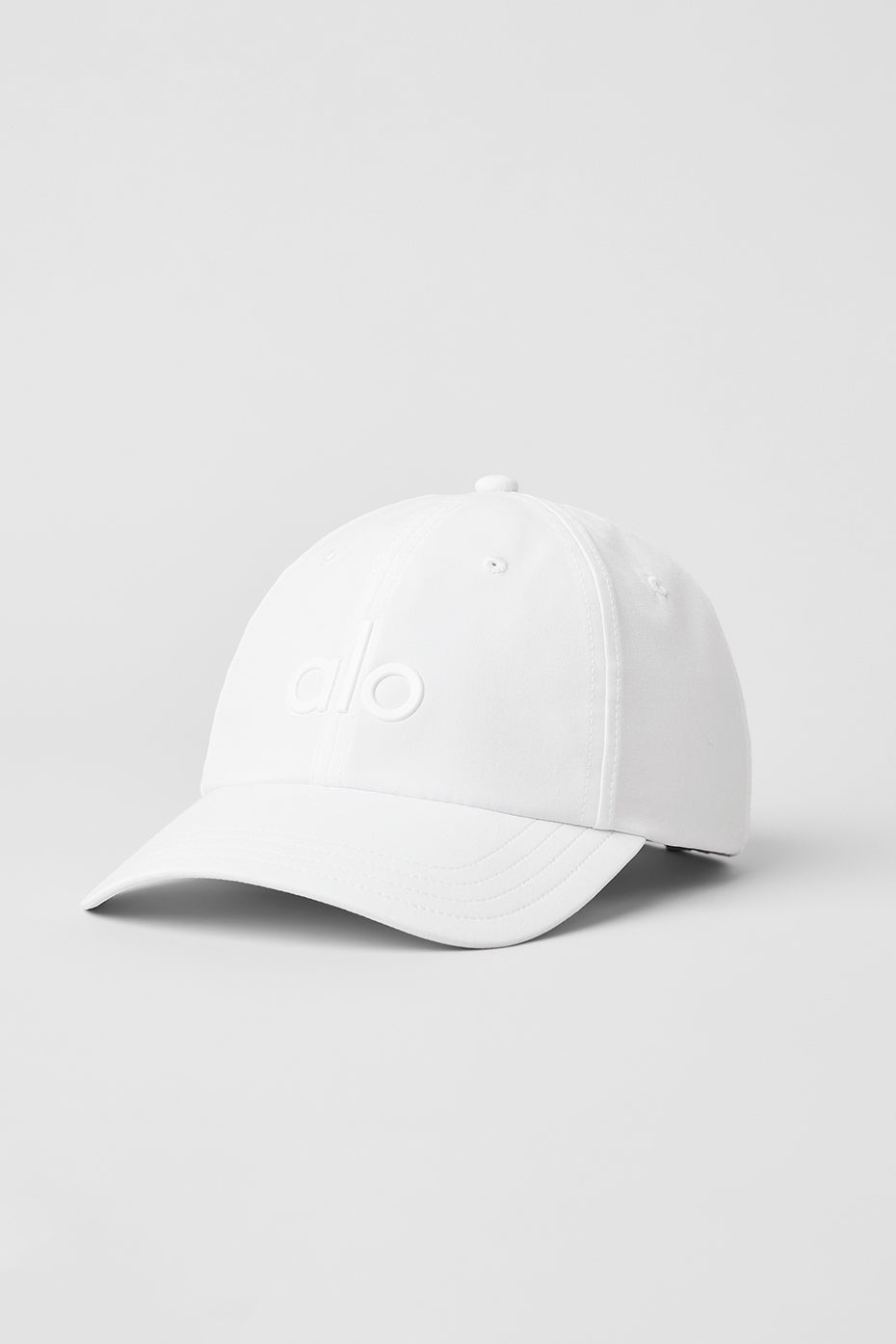 Front view of white baseball cap on a fitness bench near the ocean.