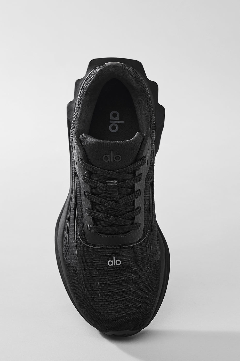 Person wearing ALO Runner shoes jogging on city streets.