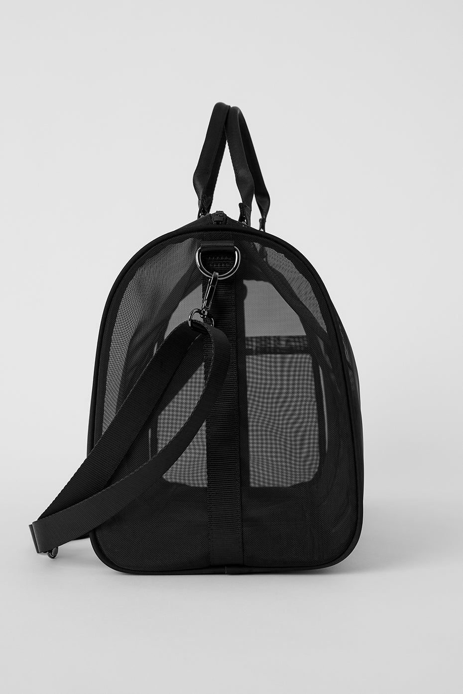Transparent weekend duffle bag standing upright with beach items.