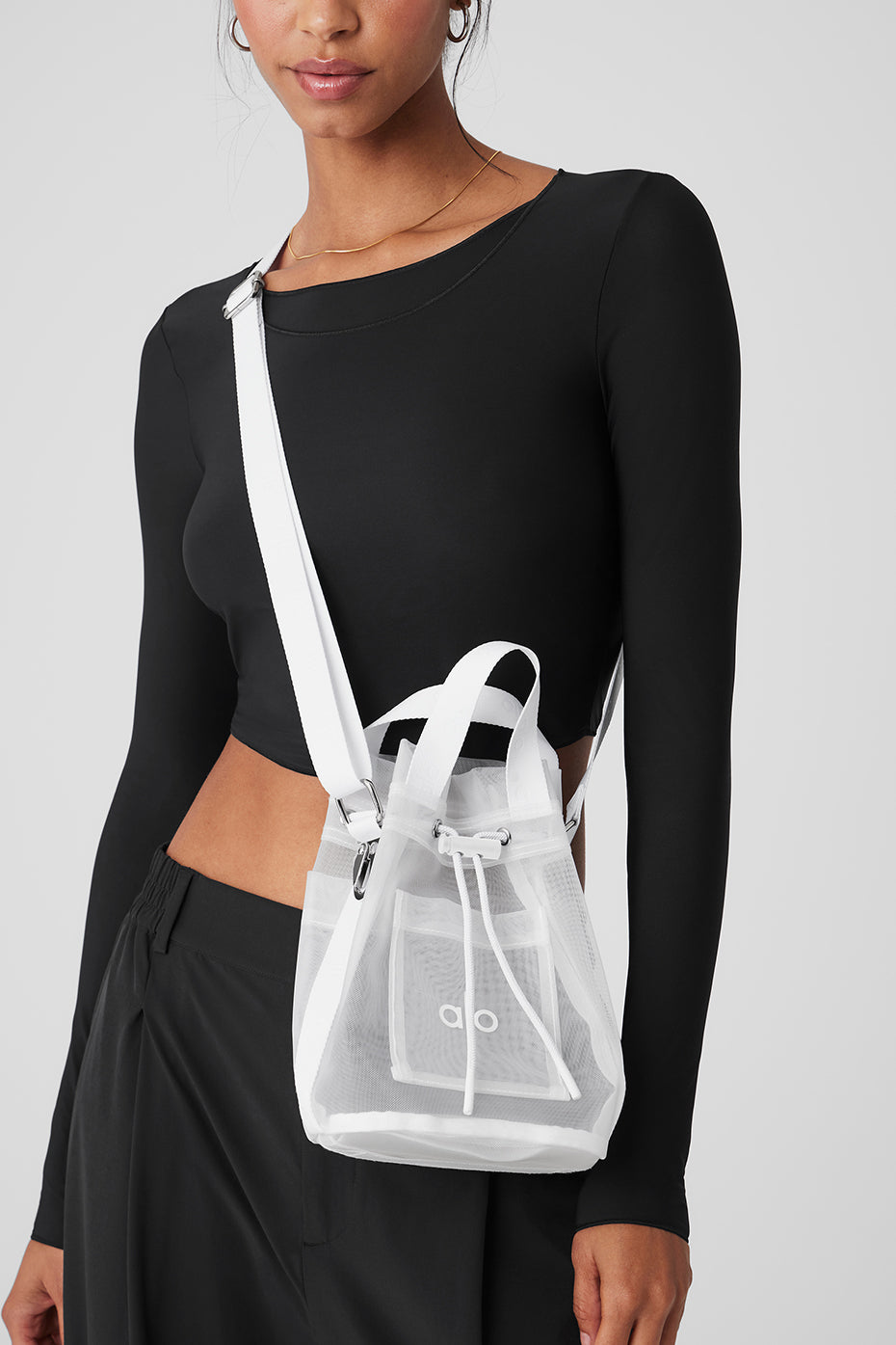 White sheer cross body bucket bag with adjustable strap and drawstring closure.