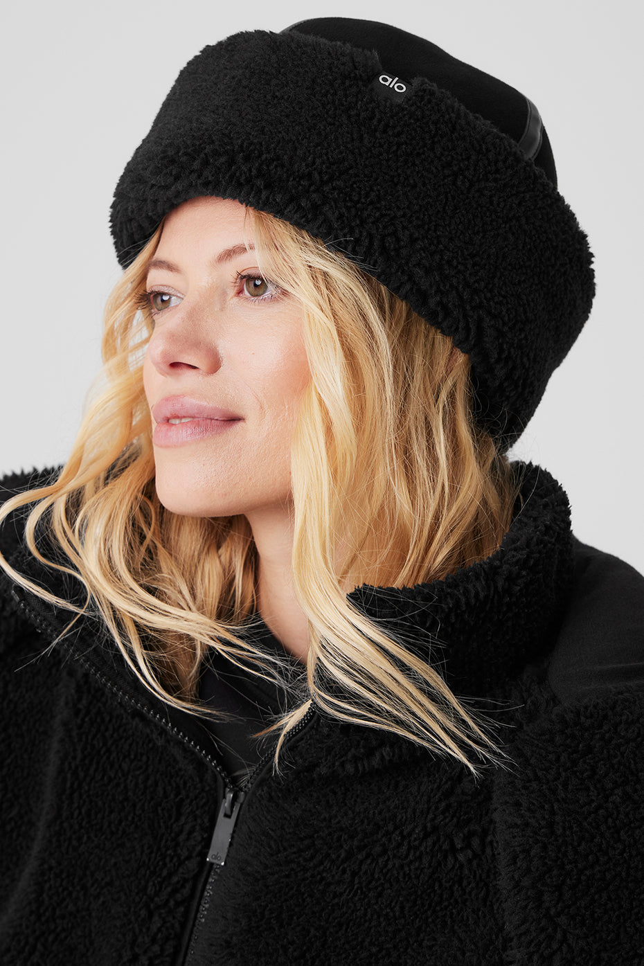 Close-up of the black sherpa winter hat showcasing the plush brim and suede crown.