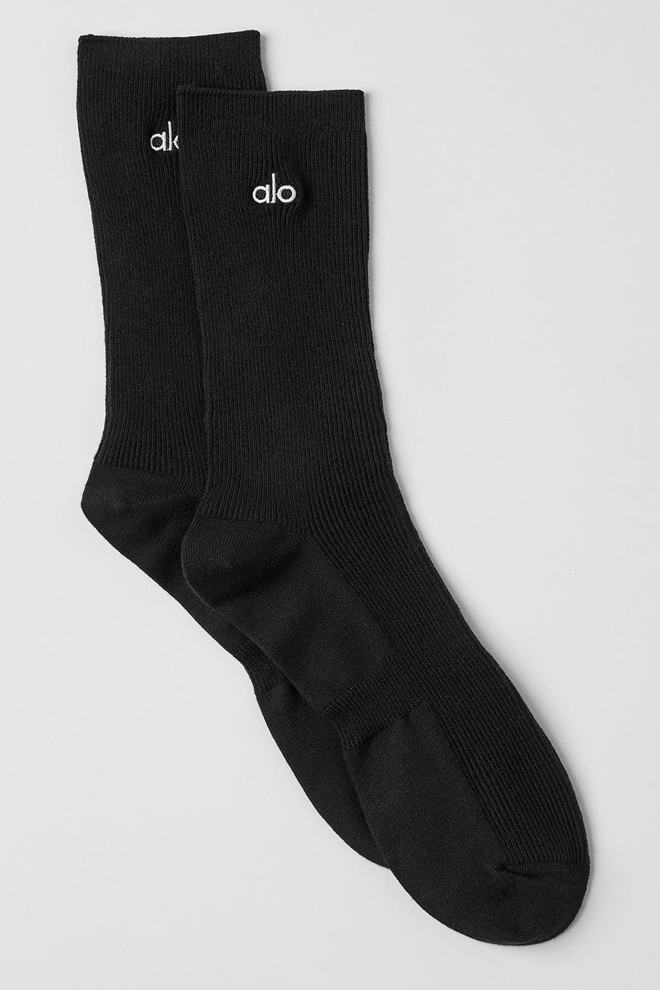 Unisex black half-crew sock with silver logo patch on a white background