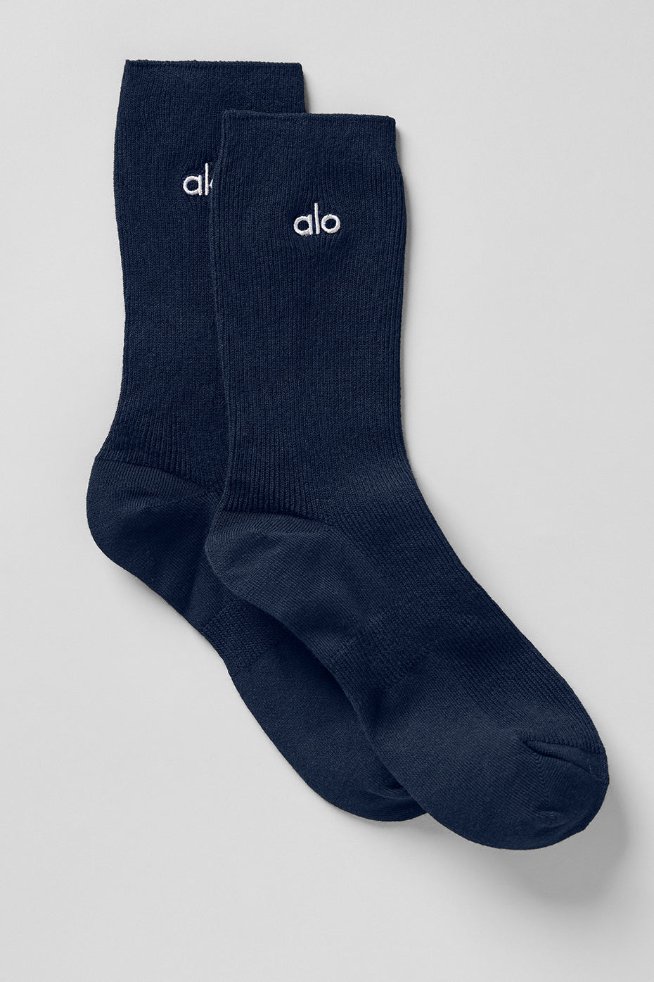 Navy half-crew athletic socks with silver logo patch on a model's foot