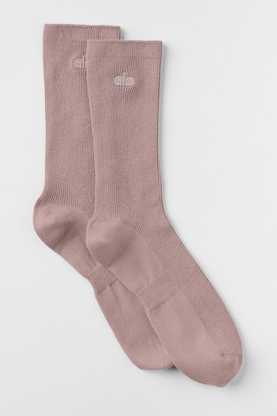 Close-up of taupe unisex socks with silver logo patch shown in indoor lighting