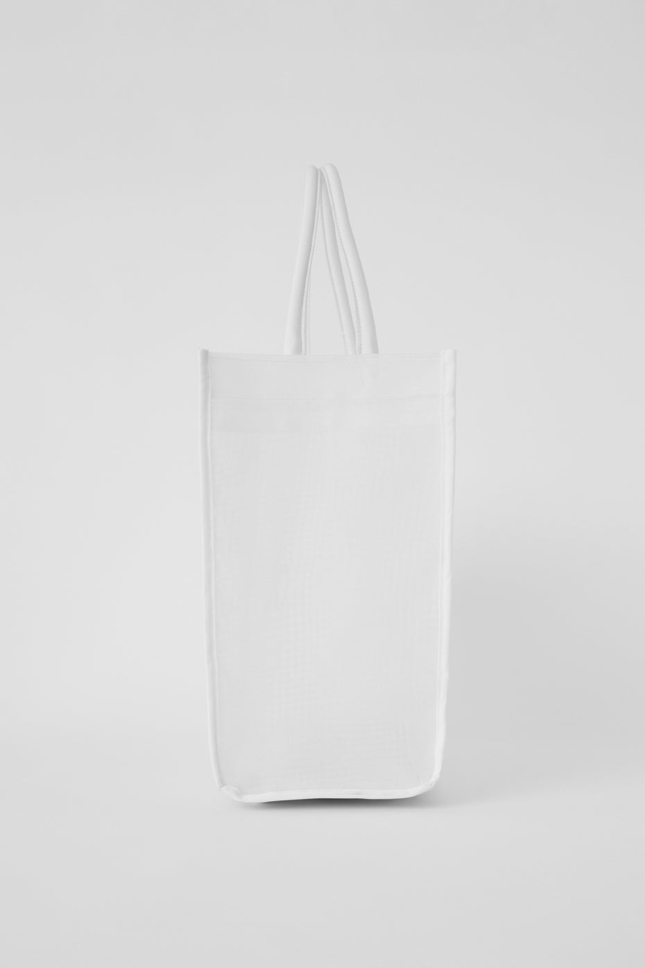 Lifestyle shot of white mesh tote hanging on a shoulder during a weekend market trip