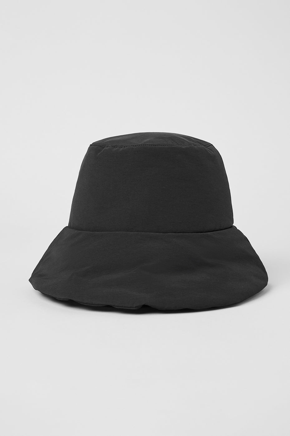 Person wearing puffer hat at a sunny outdoor cafe