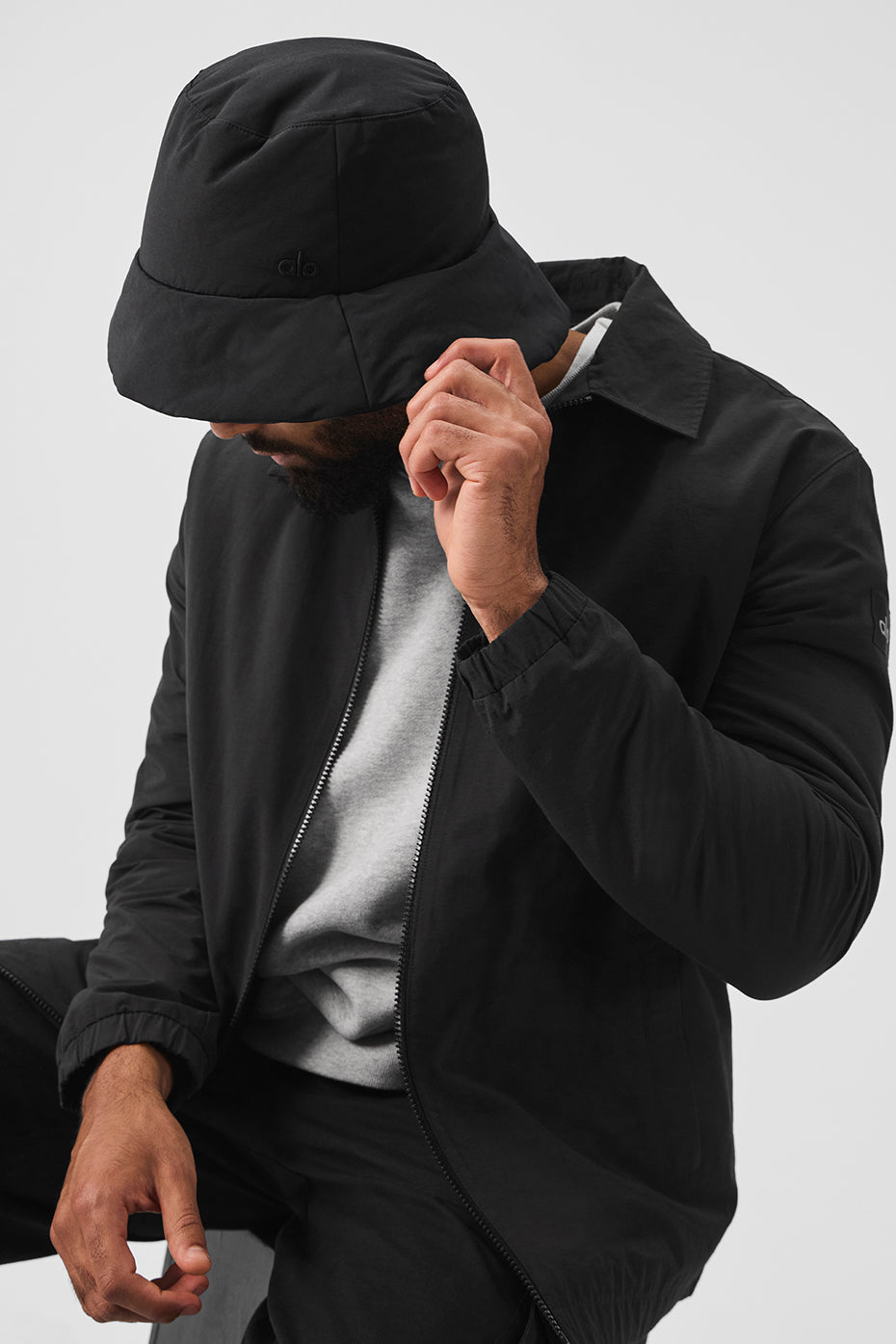 Close-up of black crochet bucket hat showing embroidered logo detail