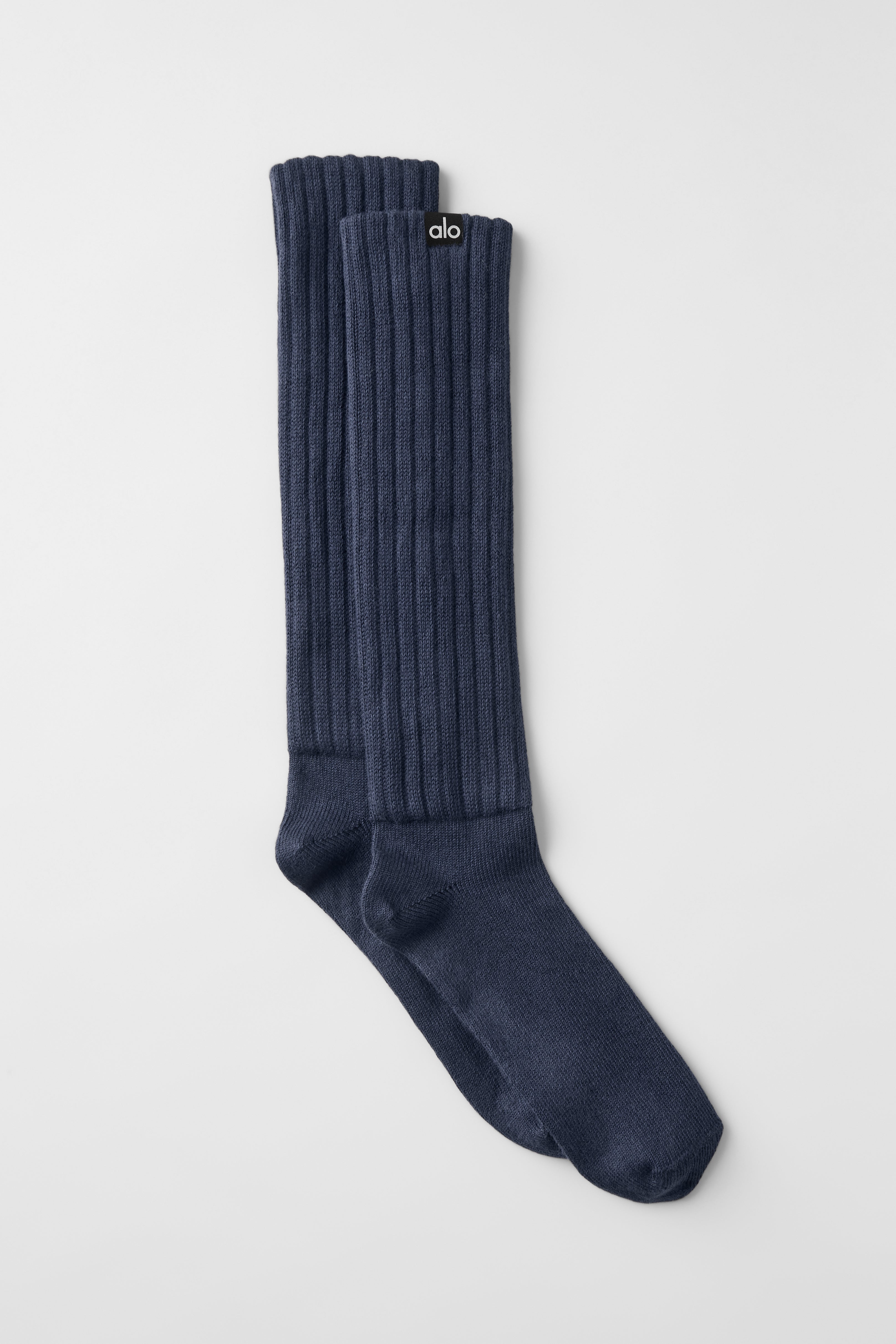 Navy slouch scrunch socks laid out on a wooden surface, highlighting the texture.