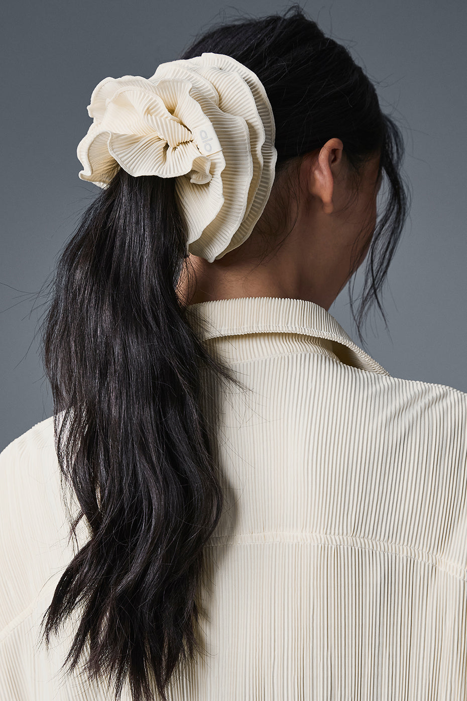 Close-up of the plisse scrunchie’s delicate folds, resting on a wooden table