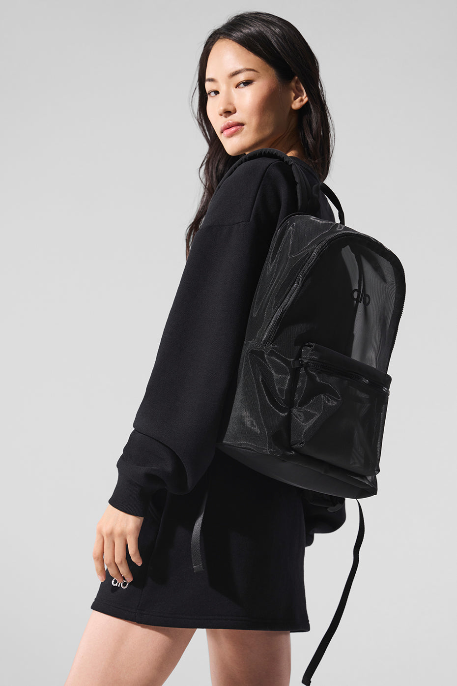 Sheer mesh gym backpack worn over shoulder in a studio setting.