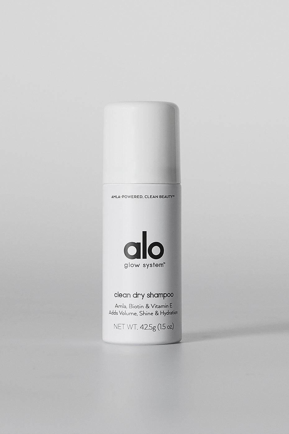 Front angle of eco-friendly dry shampoo bottle placed near hairbrush.