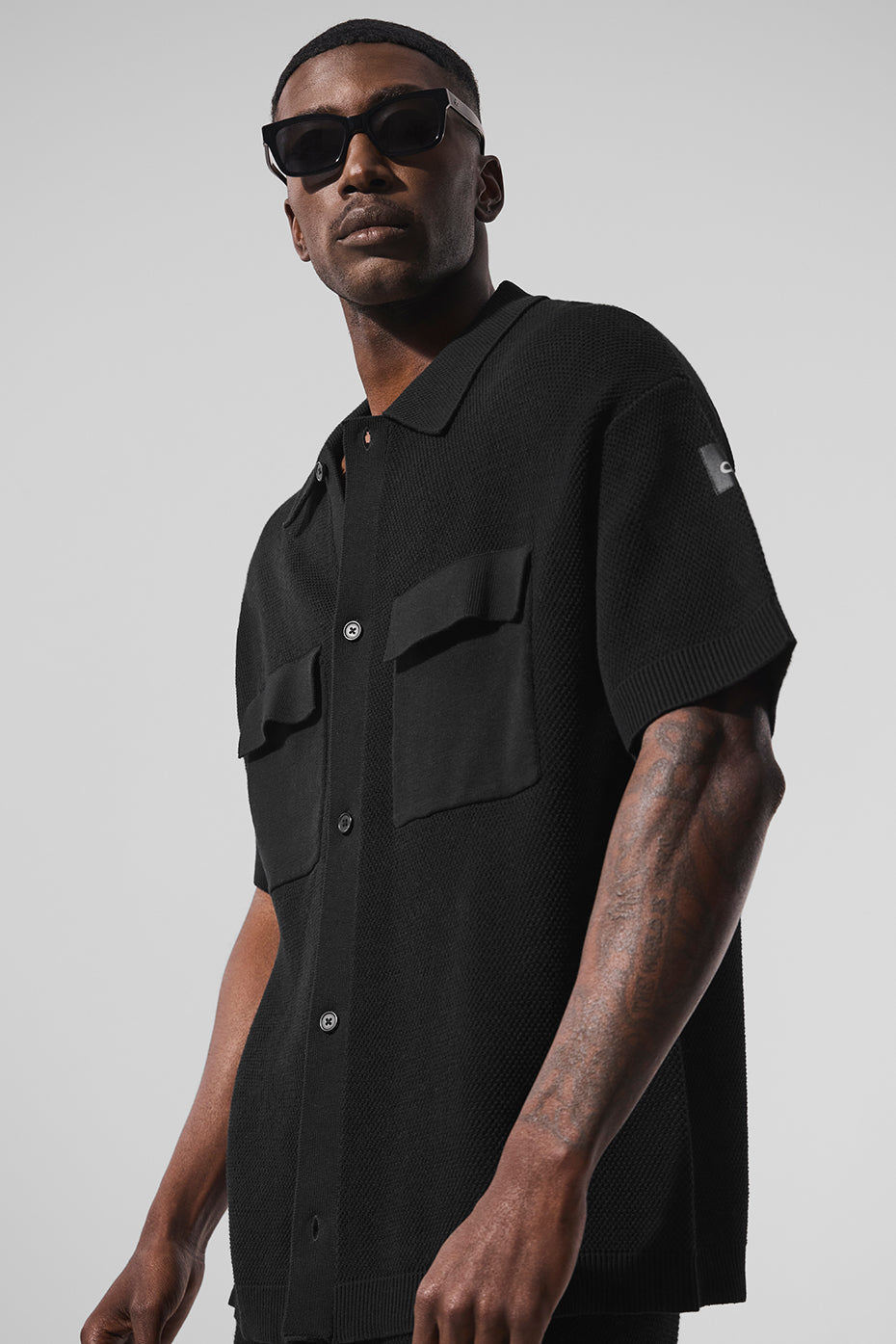 Front view of black knit short sleeve button-up sweater shirt worn casually