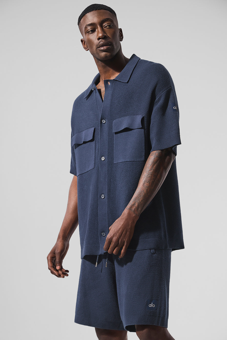 Front view of men's short sleeve button up in navy knit, styled with jeans