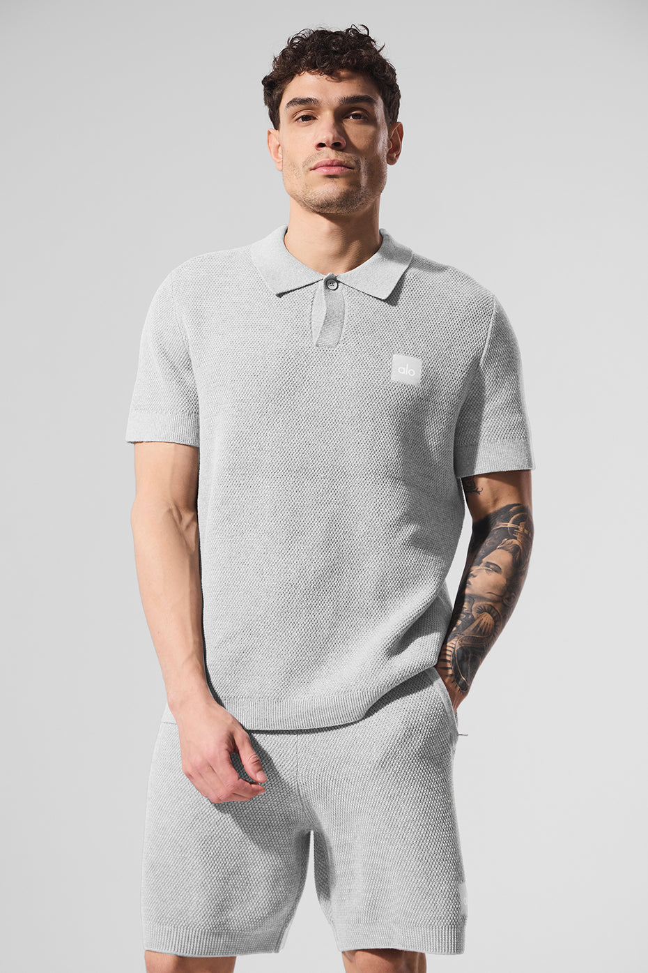 Front view of the athletic grey knit polo shirt on a model outdoors.