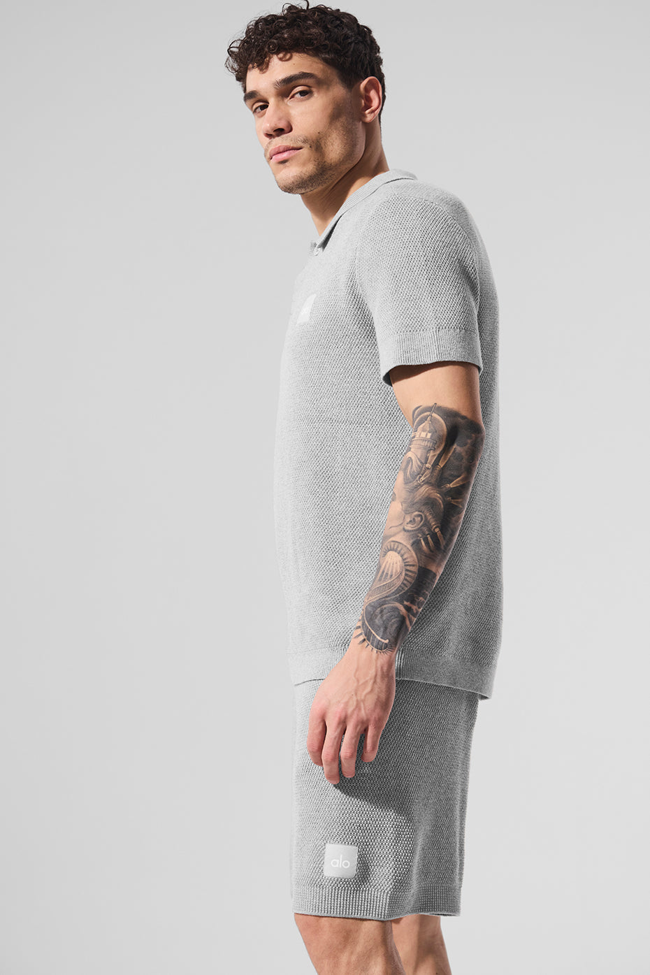 Front view of the athletic grey knit polo shirt on a model outdoors.