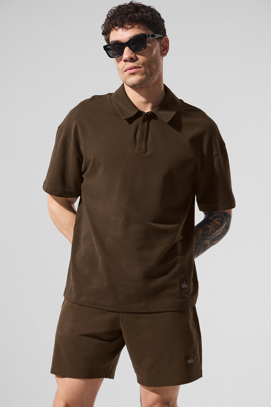 Model wearing black polo shirt standing near golf course path.