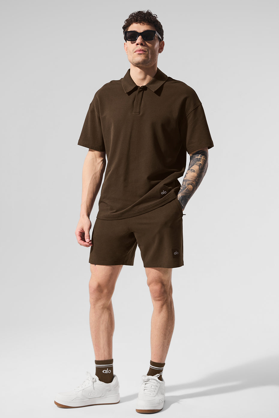 Model wearing black polo shirt standing near golf course path.