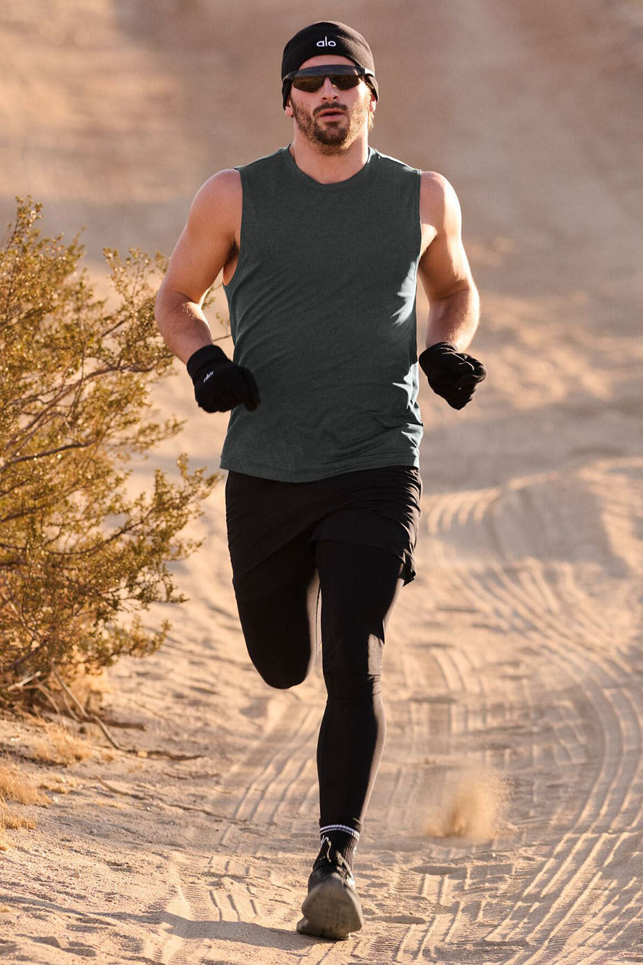 Model wearing the muscle tank paired with gym shorts and a hoodie.