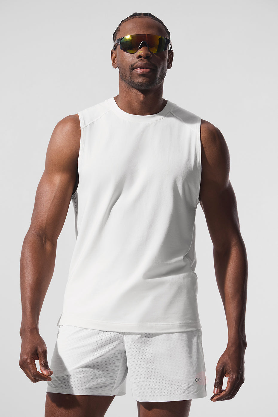 Side profile of model wearing white workout tank in a gym setting