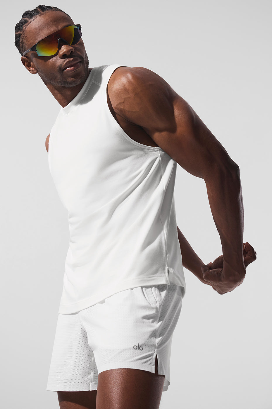 Side profile of model wearing white workout tank in a gym setting