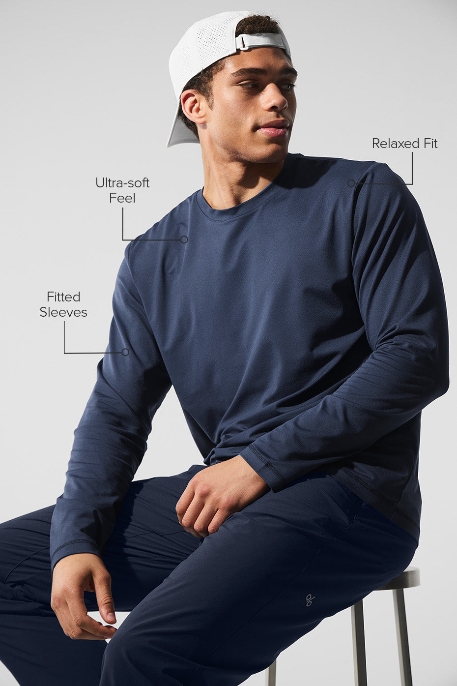Model wearing navy crewneck sweatshirt with layered long sleeve polo shirts