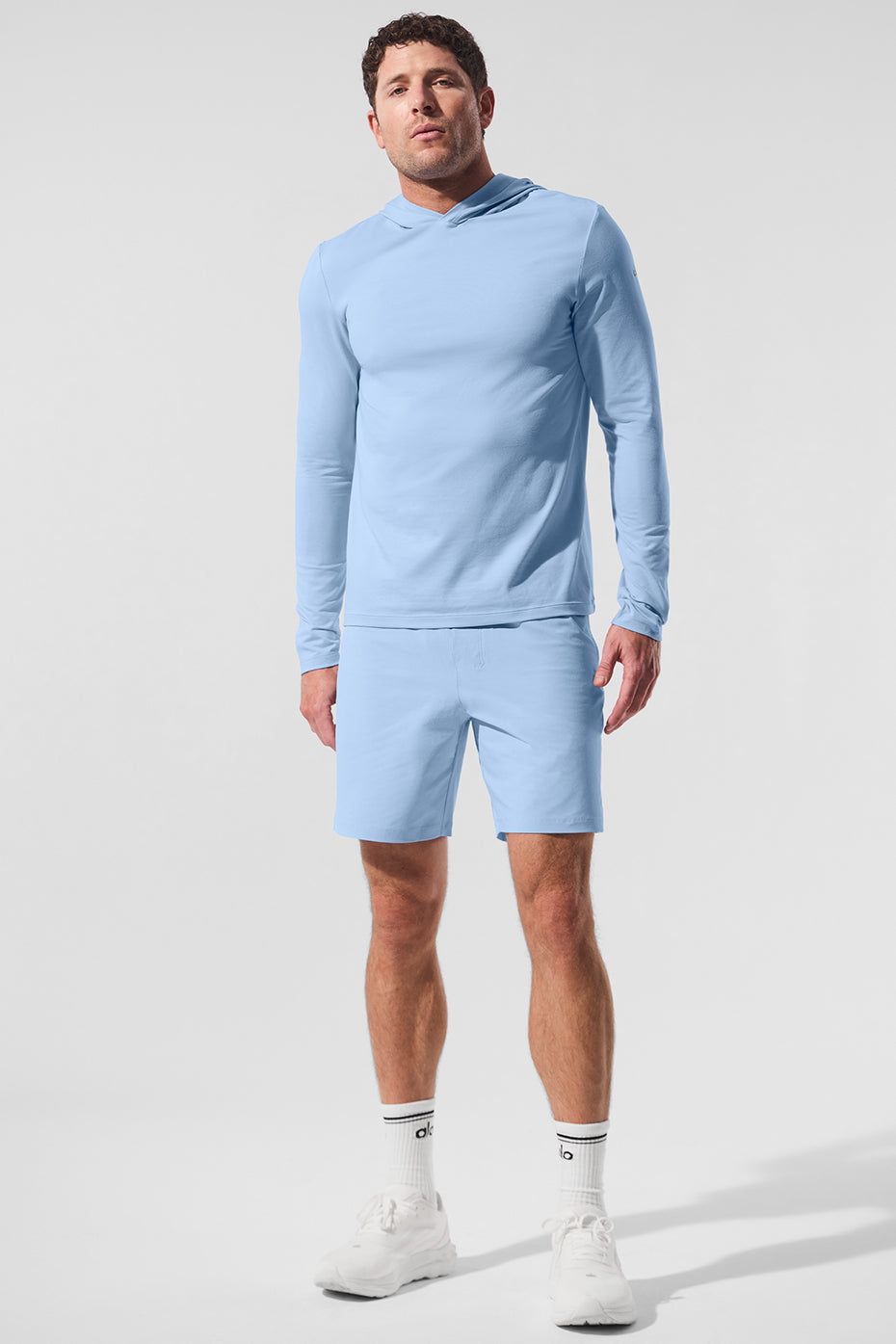 Model wearing athletic long sleeve hooded shirt outdoors in seashell blue color