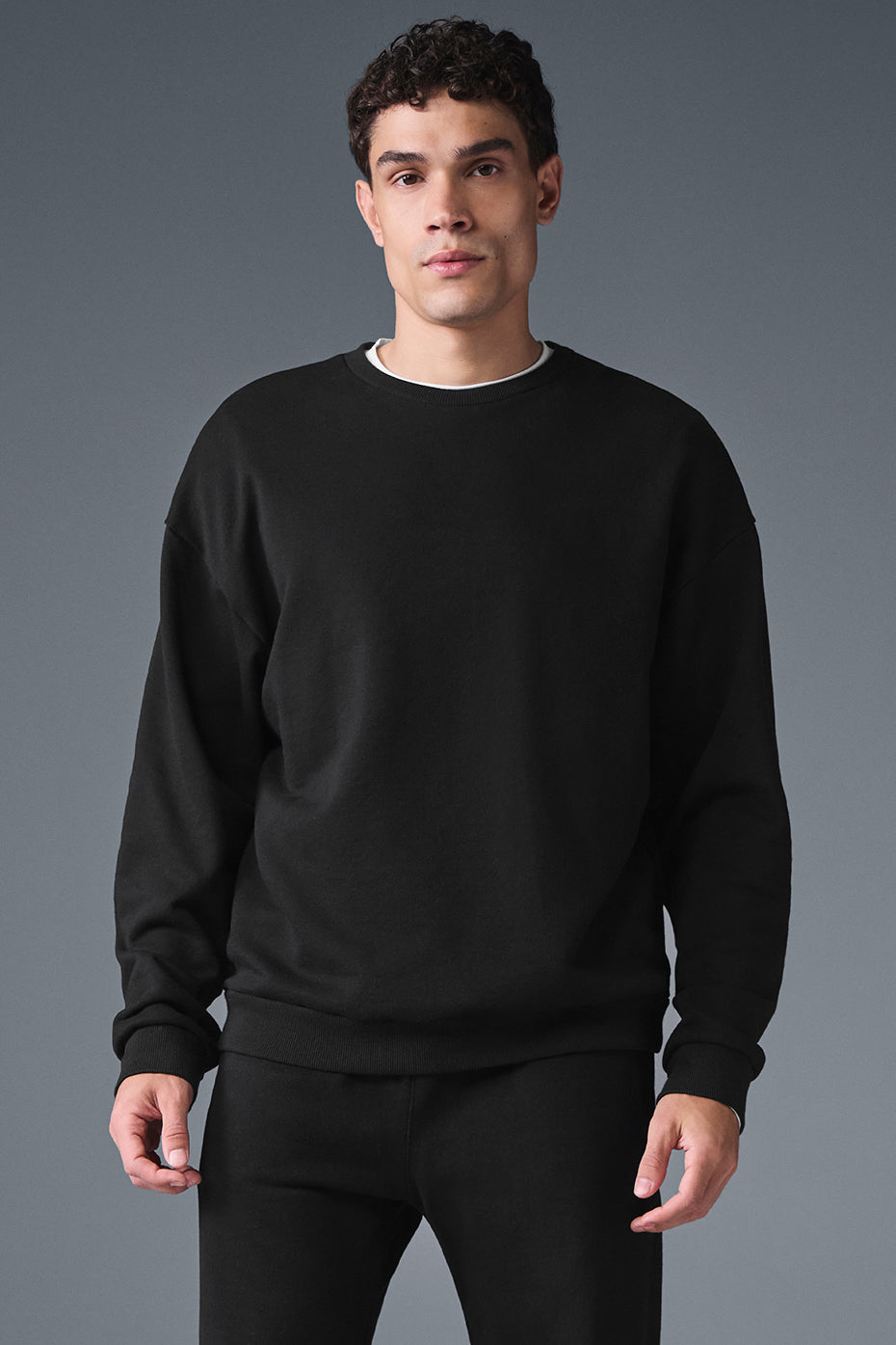 Close-up of the black crew neck pullover's cuffed hem and French terry fabric texture