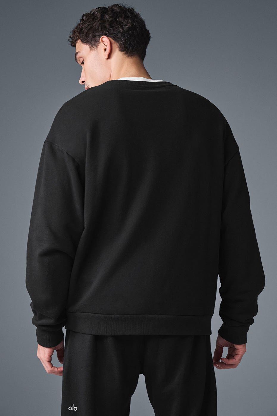 Person stretching outdoors in the black crew neck pullover, emphasizing comfort and breathability