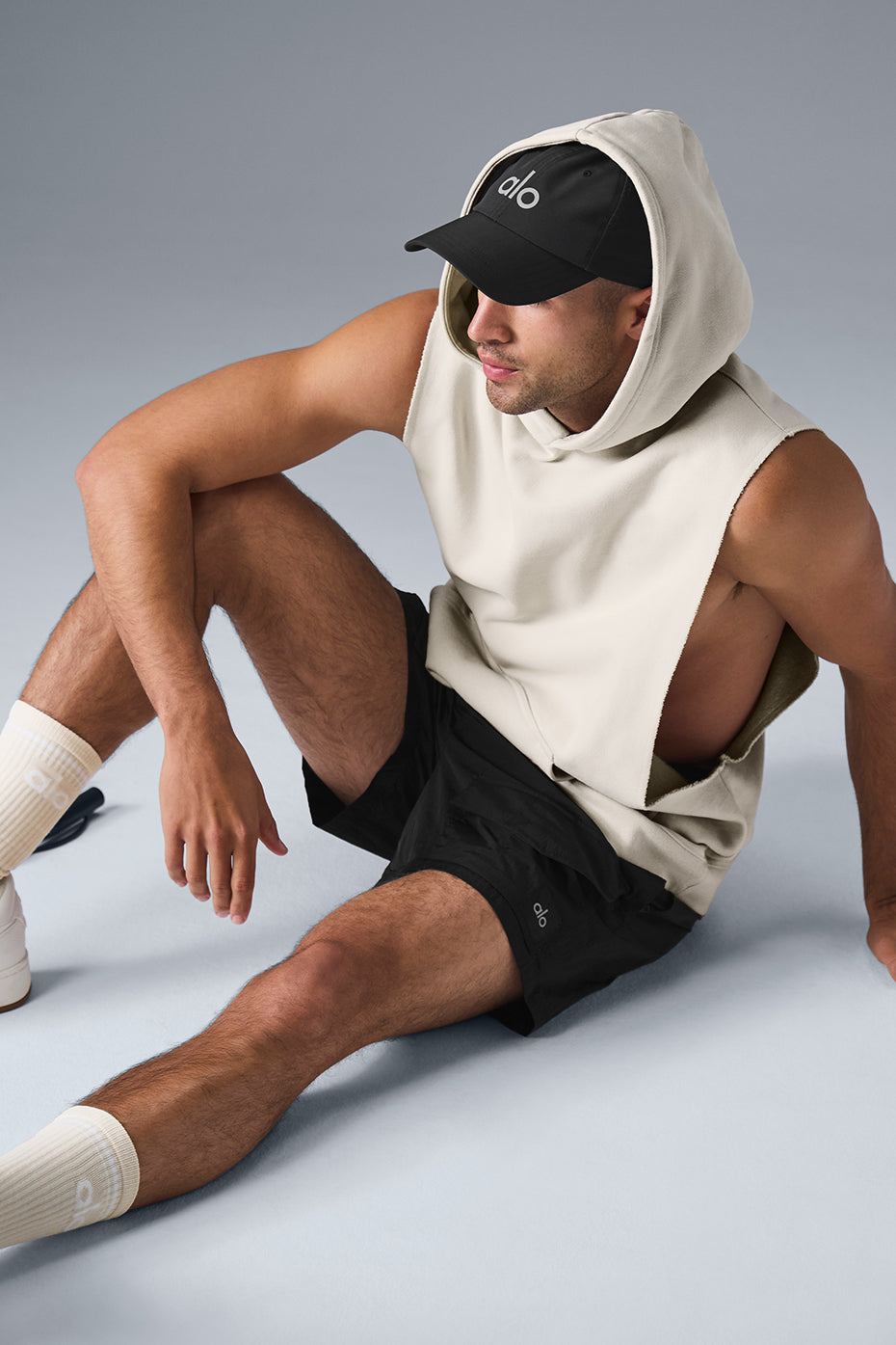 Front view of a sleeveless hoodie on a model in a gym setting