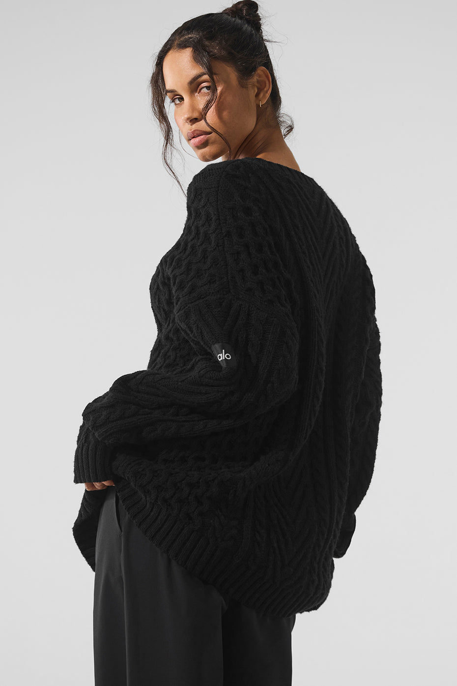 Close-up of the chunky cable knit detailing on a mens black sweater
