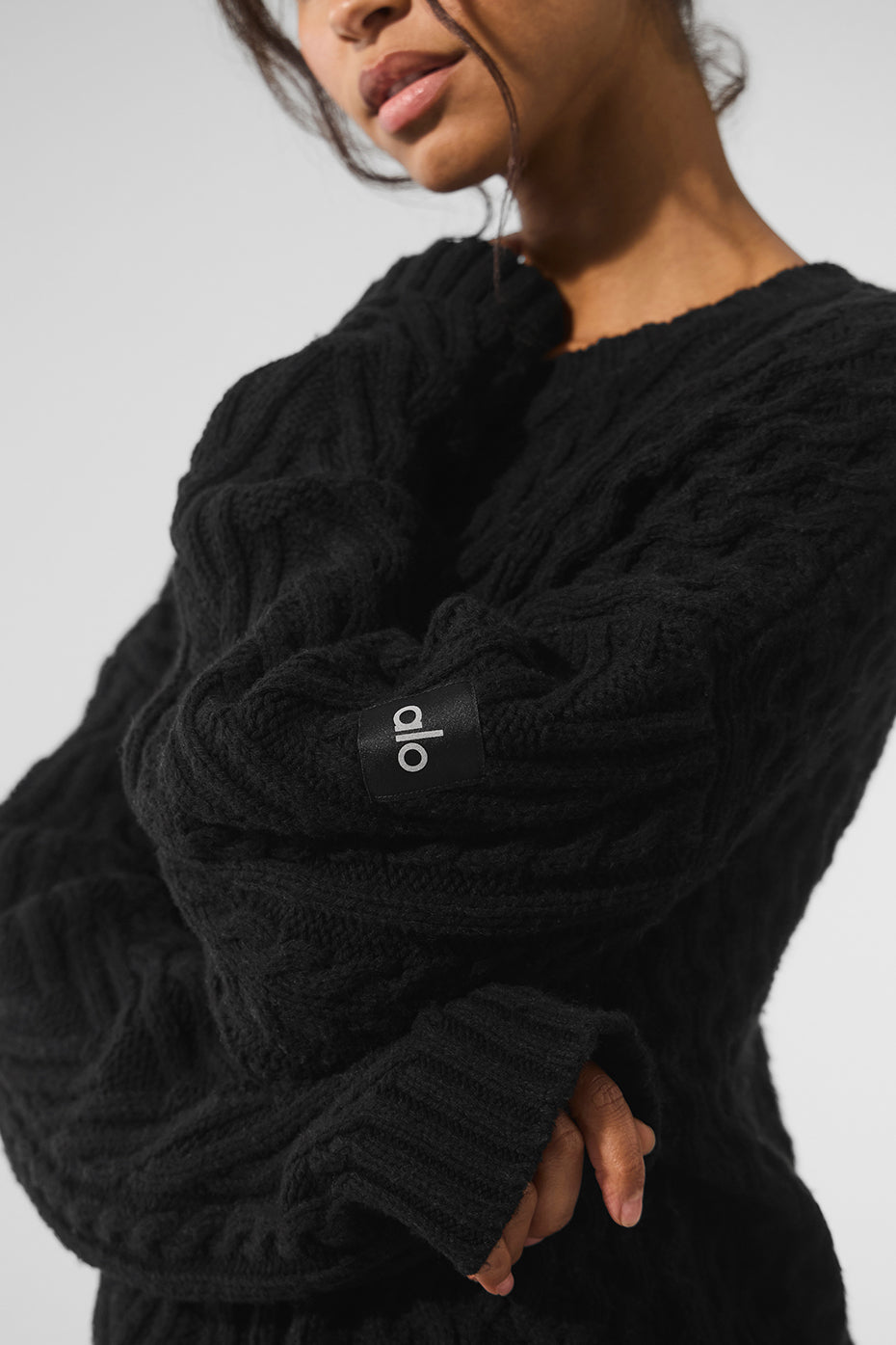 Model wearing a black cable knit sweater paired with jeans for a casual outing