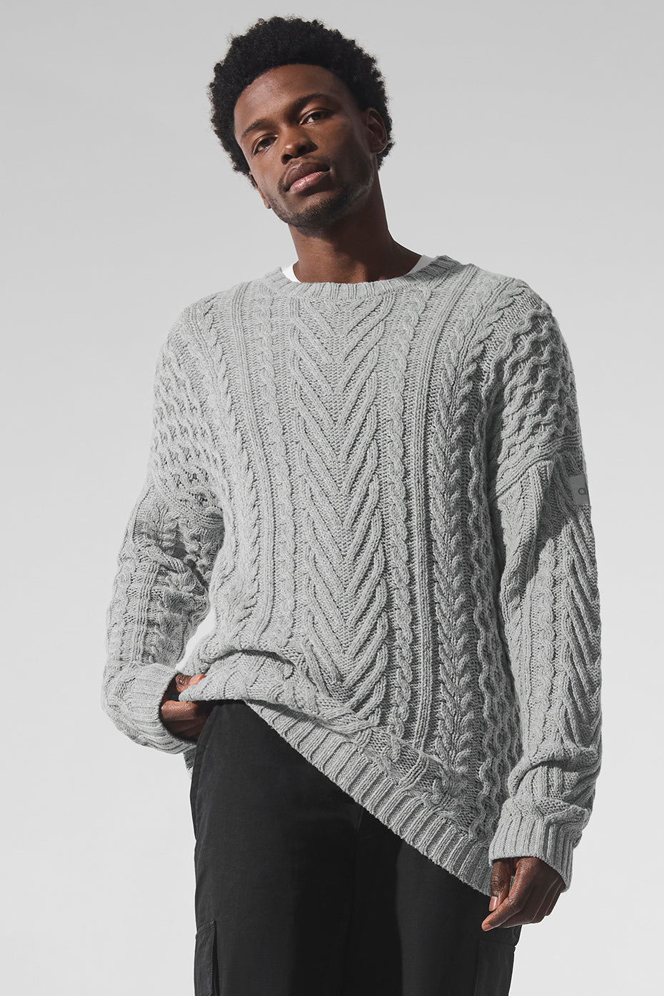Front view of chunky knit sweater styled with denim in urban winter setting