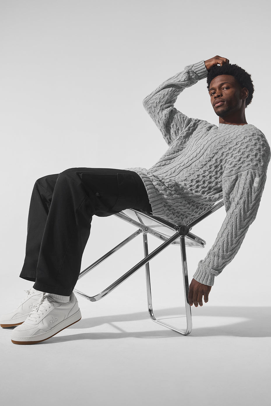 Front view of chunky knit sweater styled with denim in urban winter setting