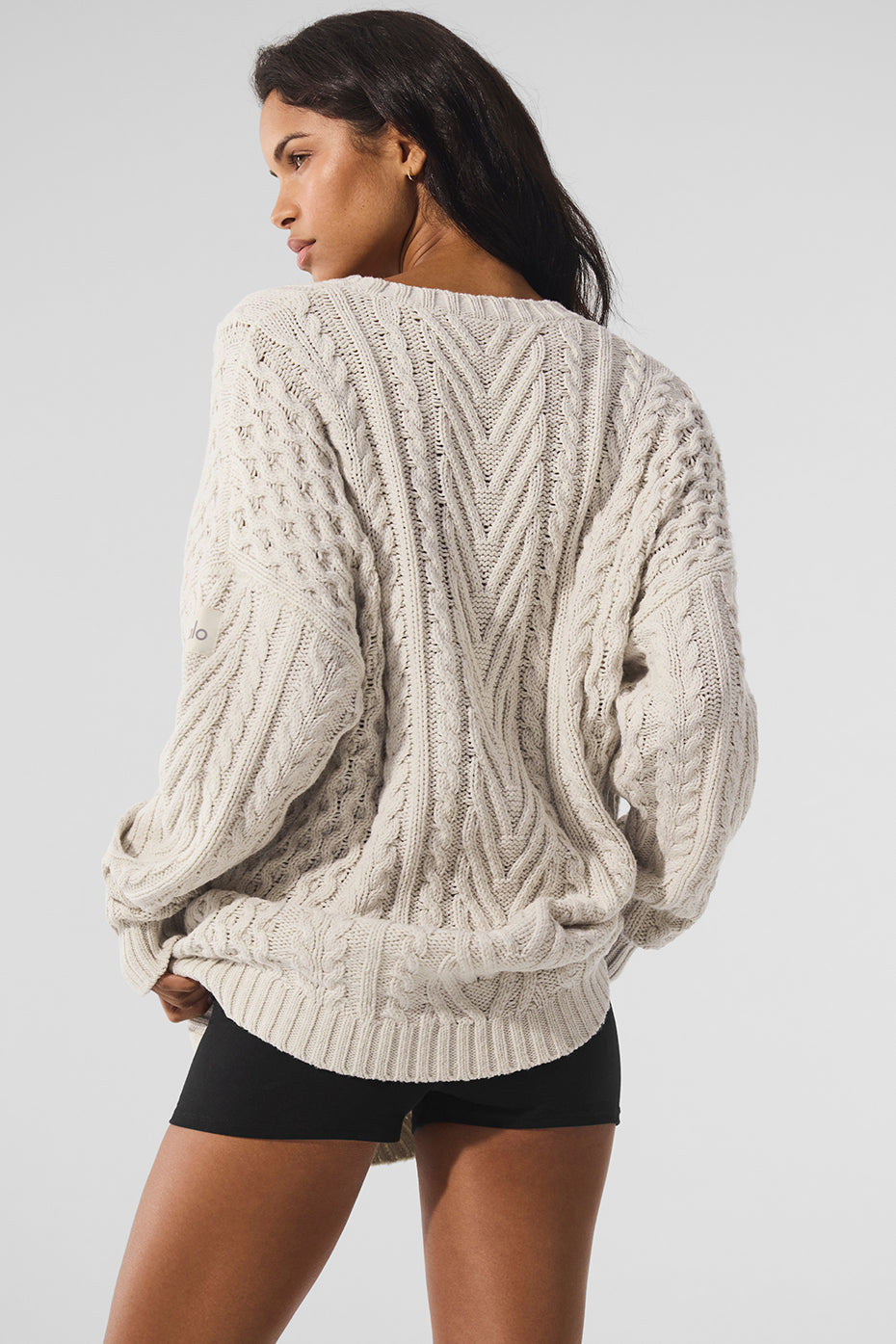 Side angle of a cozy crew neck sweater, showcasing its cable knit details.