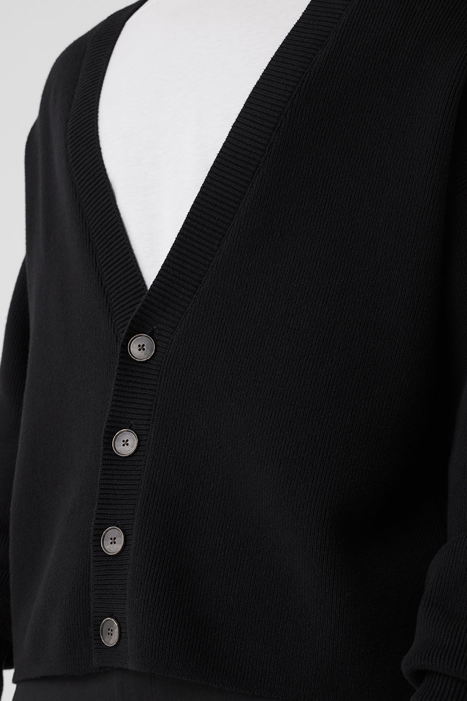 Front view of the black cardigan showing the four-button closure and ribbed cuffs