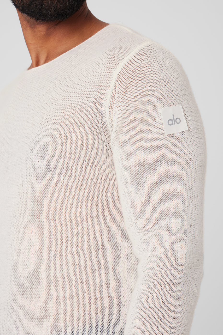 Front view of man wearing ivory cashmere sweater against winter backdrop.