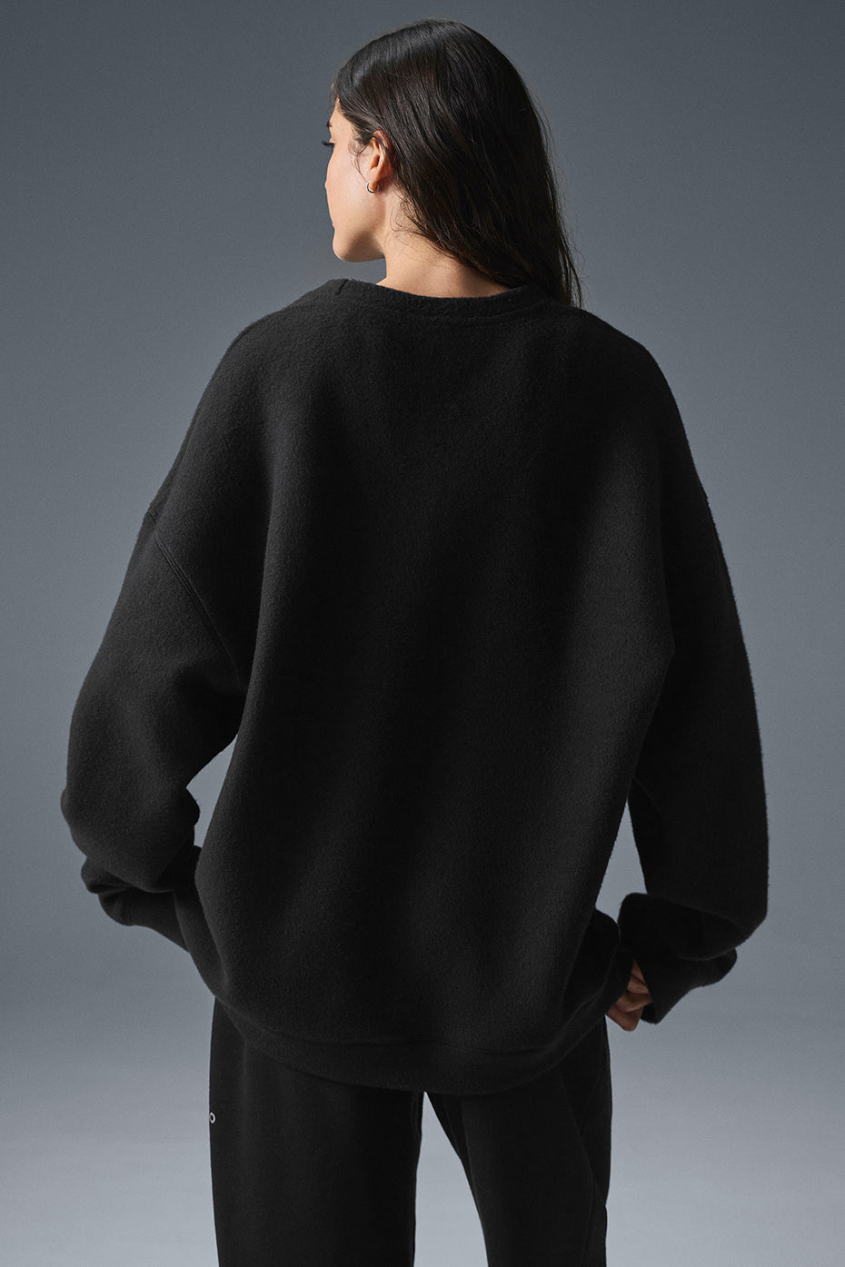 Lifestyle shot of a woman wearing the black sweatshirt while relaxing.
