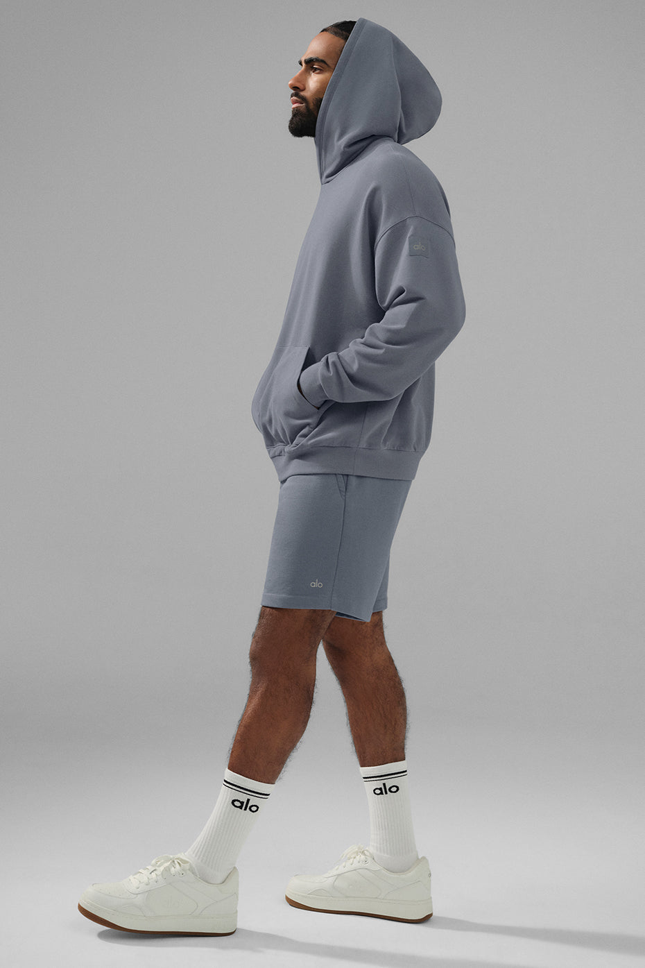 Lifestyle image of a man wearing the grey hoodie paired with trench coat for a stylish outdoor look