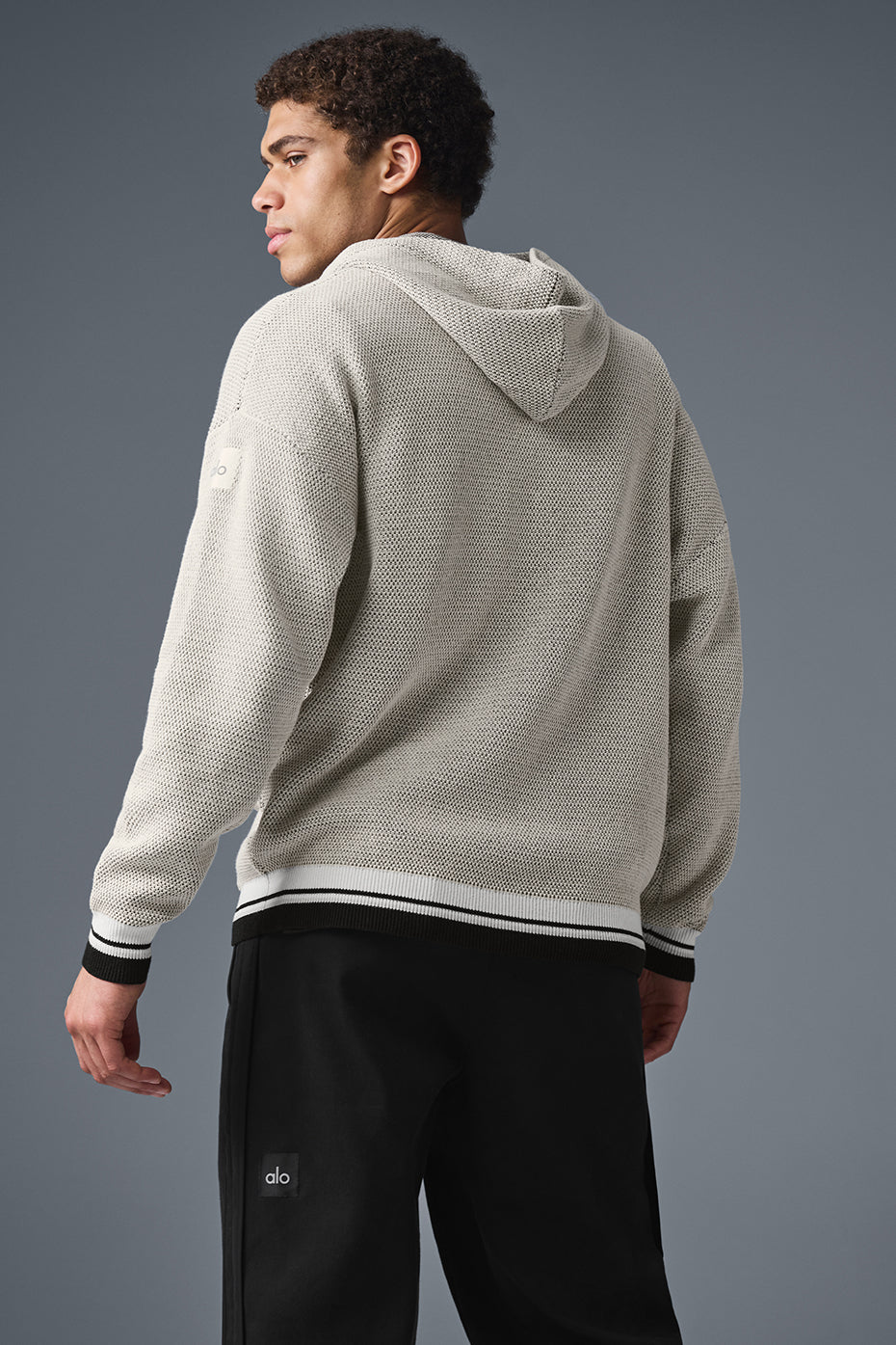 Front view of knitted hoodie styled with denim, showing pocket detail
