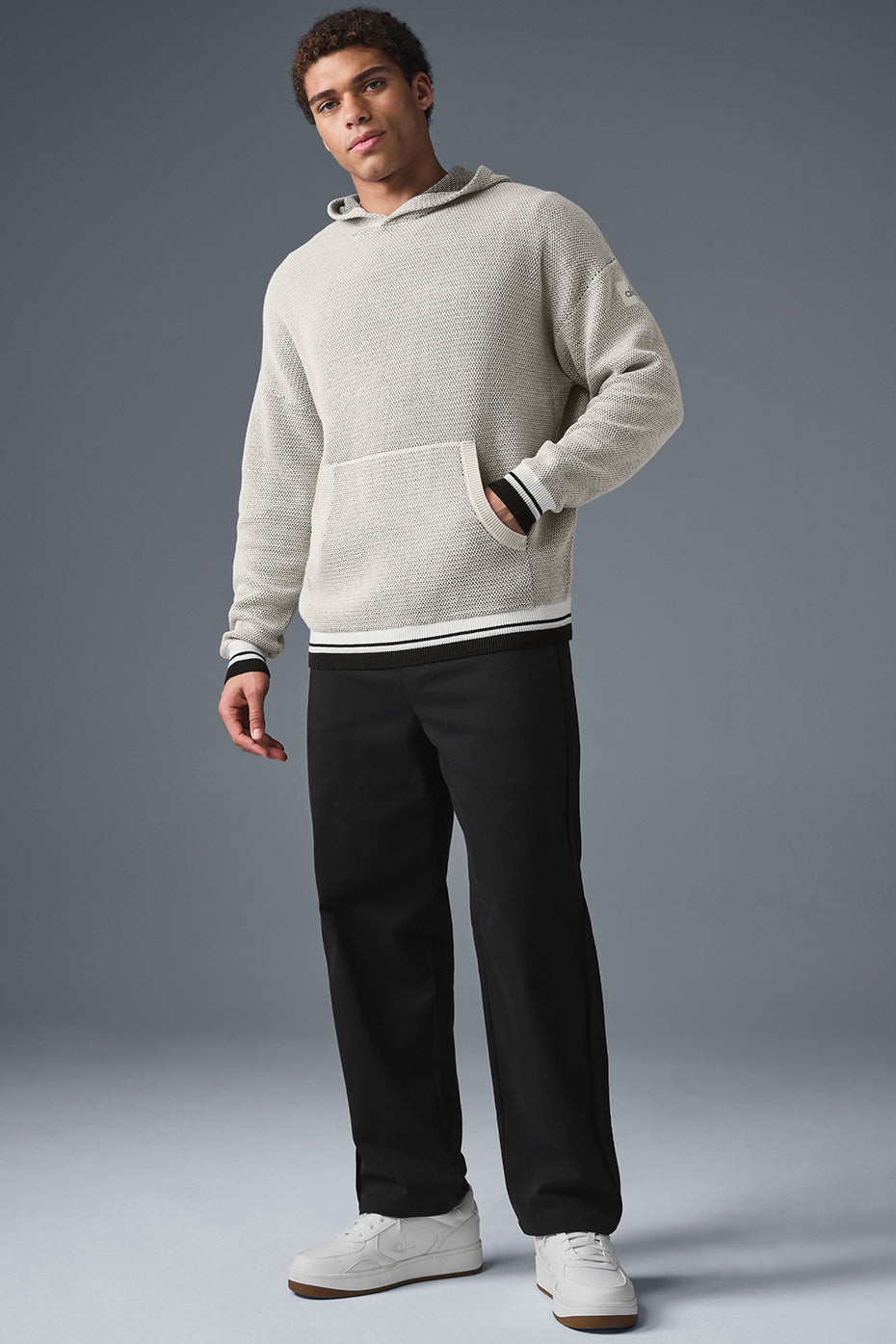 Front view of knitted hoodie styled with denim, showing pocket detail