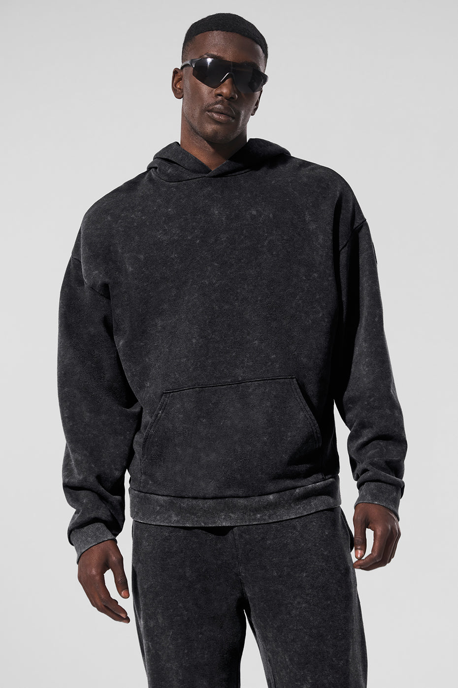 Black vintage wash hoodie laid flat, showcasing faded detailing and front pocket.